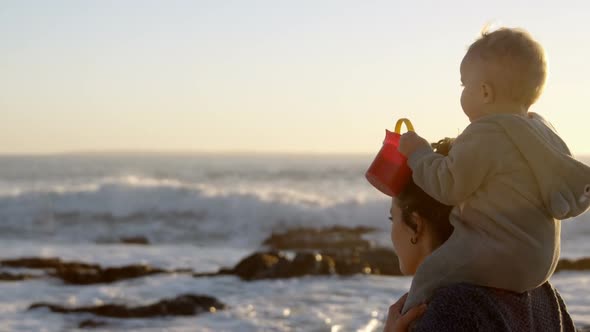 Mother playing with her baby boy in the beach  alt