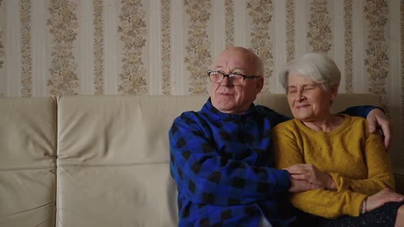 Senior Happy Couple Enjoying Time Together While Sitting on the Couch and Looking at the Window alt