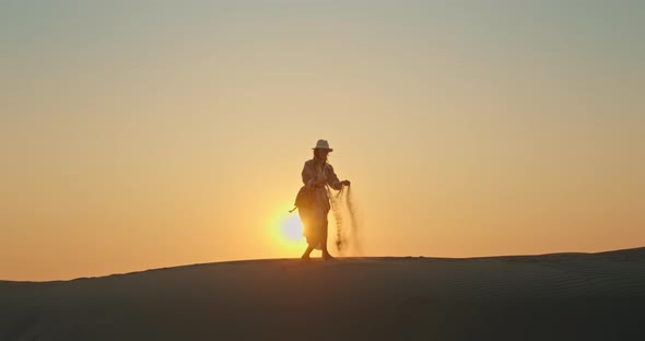 Happy Woman with Sand Blowing Away By the Wind with Golden Sunset on Background alt