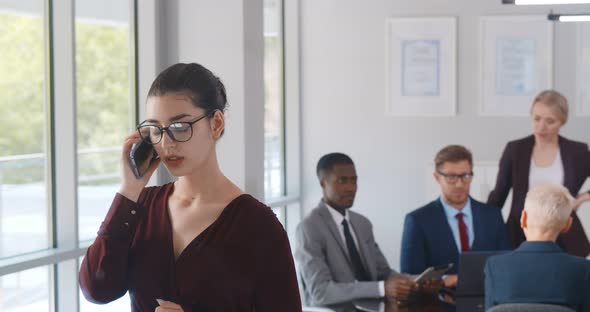 Young Serious Businesswoman Having Phone Call at Workplace alt