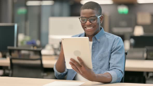 Successful Young African American Man Celebrating on Tablet in Office alt