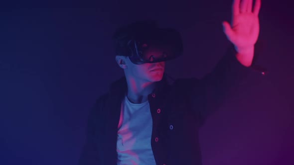 Close Up Young Man Virtual Reality Headset Playing Game Touching Something Standing Room Neon alt
