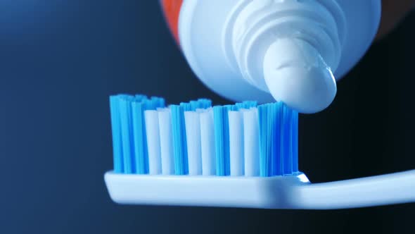 Dental Health - Squeezing White Toothpaste From a Tube Onto a Toothbrush.