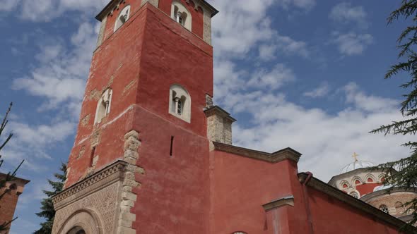 Red tower of Zica monastery and blue cloudy sky 4K tilting footage