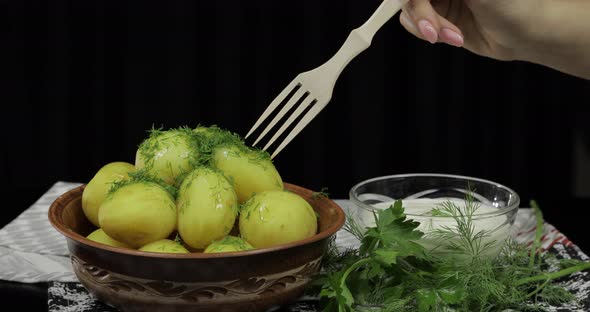 Woman's Hand Takes Boiled New Delicious Potato Using Wooden Fork alt