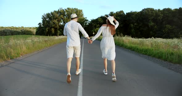 Couple Running on Countryside Road Backview