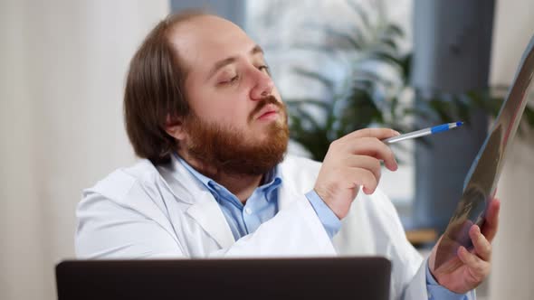 Qualified Family Doctor Wearing Coat and Videocalling Patient Showing Xray alt