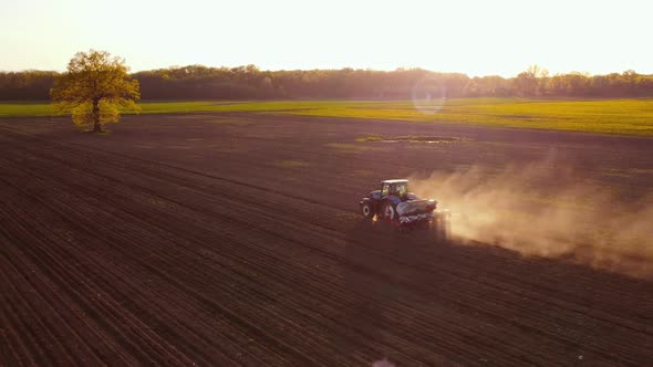 Tractor Working in Field at Sunset alt