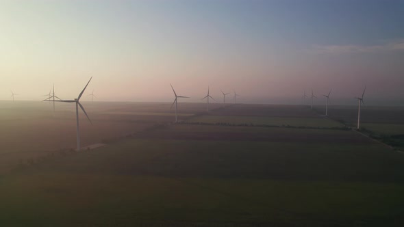 Windmills with rotating wings at sunrise or sunset or sunrise.