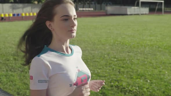 Athletic Young Girl Runs in the Stadium. Slow Motion alt