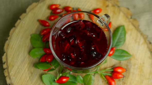Top View Healing Herbs And Red Berries In A Cup, Tea Made From Medicinal Rose Hips On A Wooden alt