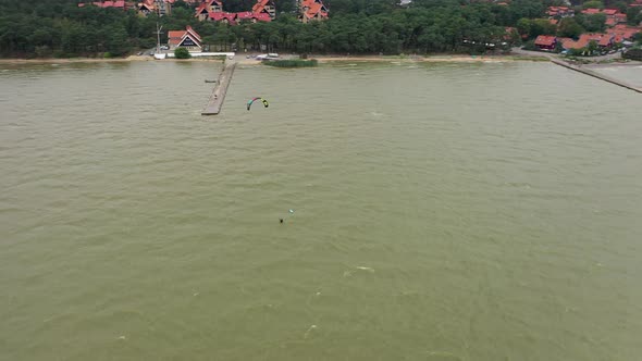 AERIAL: Rotating Shot of Young Surfer Resting in the Bay of Baltic Sea alt