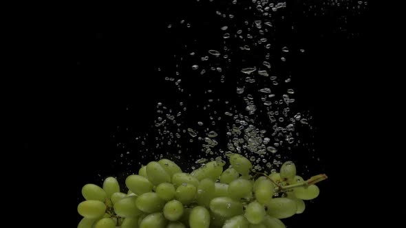 Slow Motion Green Grapes Falling Into Transparent Water on Black Background alt