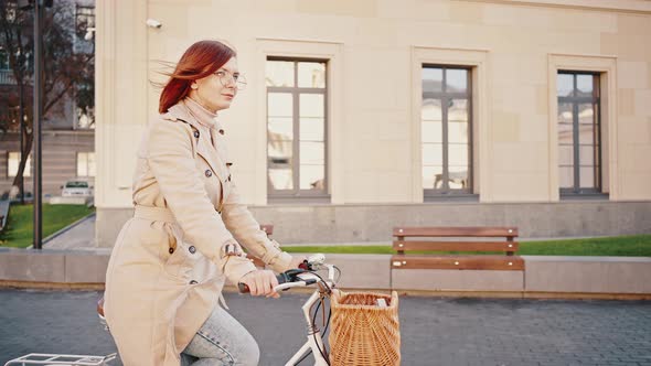 Young Female is Smiling Riding Bicycle with Basket By City Square alt
