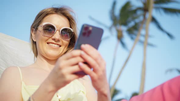 Beautiful Woman Using Smartphone Outdoor Tropical Island with Green Palm Trees alt