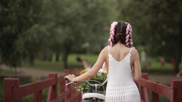 View From Back of Girl in White Dress Riding Bicycle in Park