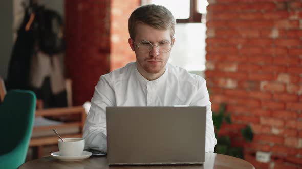 Freelancer Man is Working with Laptop in Cozy Cafe and Drinking Coffee Remote Work Model and alt