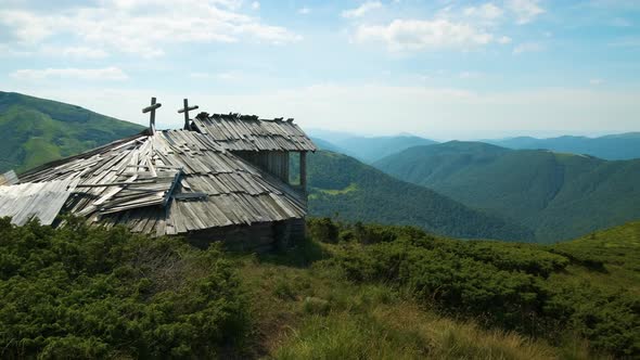 Summer mountain landscape with old forsaken tourist shelter on grassy hills and distant peaks alt