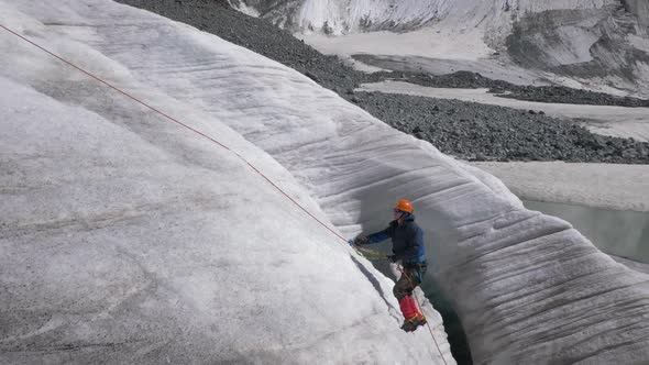 Mountaineer Man in Crampons Is Using Ascender on Fixed Rope on Steep Slope in Mountains alt