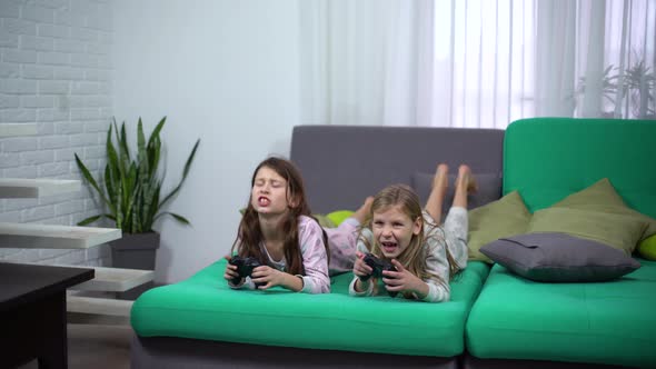 Two Kids in Pajamas Playing with Game-Pads at Home alt