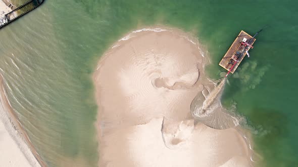A bird's eye view of the beach being filled in with sand in summer. alt