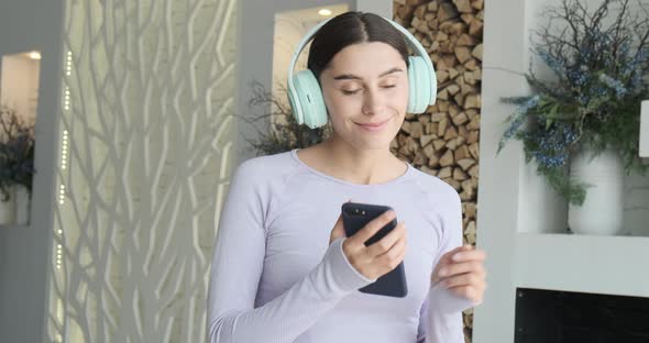 Happy Cheerful Young Woman Dancing Alone at Home and Using Smartphone for Listening Music alt