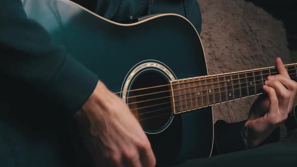 Man Plays a Pick on a Modern Guitar in the Dark alt