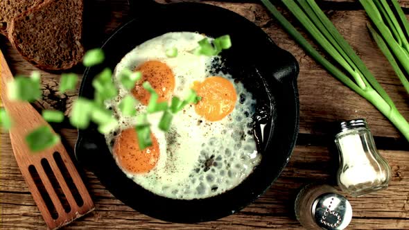 Super Slow Motion Chopped Green Onions Drops Into the Pan with Fried Eggs alt