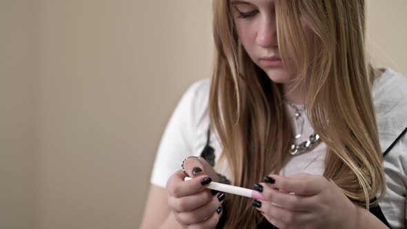 Teenage Girl Looks Fearfully at a Pregnancy Test