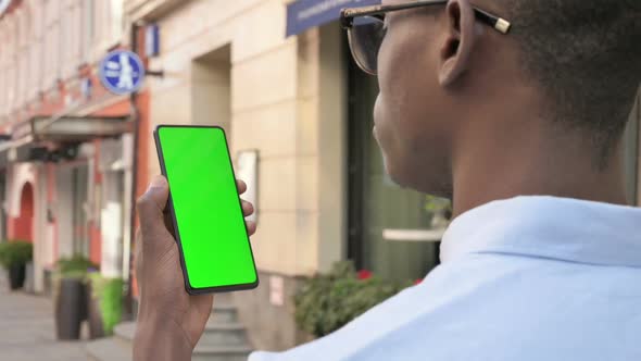 African Man Looking at Smartphone with Green Chroma Screen alt