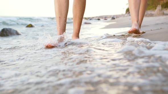 Young couple walking barefoot along the seashore