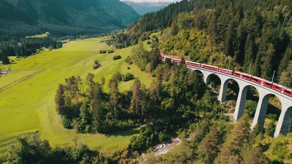 Aerial View of a Moving Red Train Along the Landwasser Viaduct in Swiss Alps alt