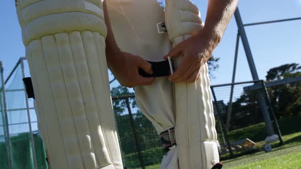 Cricket player tying his batting pads during a practice session alt