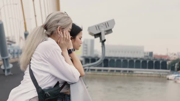 Asian lesbian couples enjoying traveling and talk while standing on the bridge.