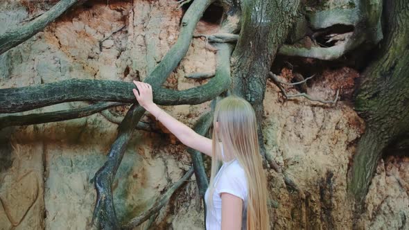Young Blonde Woman Looking on Exposed Tree Roots in Natural Loess Ravine alt