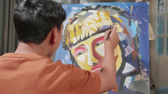 Hind View Of An Asian Artist Boy Holding Paintbrush And Thinking Before Painting On The Canvas alt
