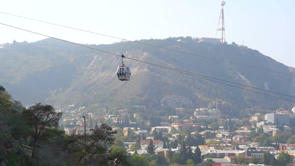 Cableway Car Hanging Above the Tbilisi City in Georgia with the View of Old Buildings on Background alt
