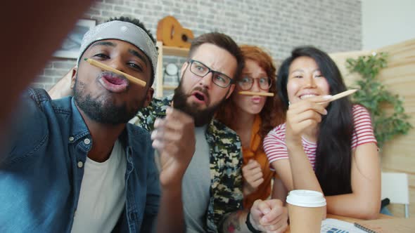 POV of Youth Taking Selfie in Office Looking at Camera Having Fun with Pencils alt