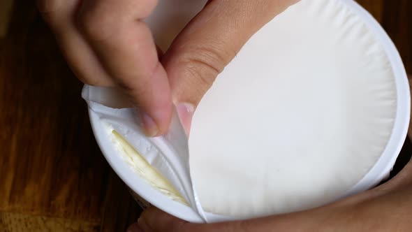 The woman opens a plastic jar with white cheese, cottage cheese, yogurt. Healthy dairy food. alt