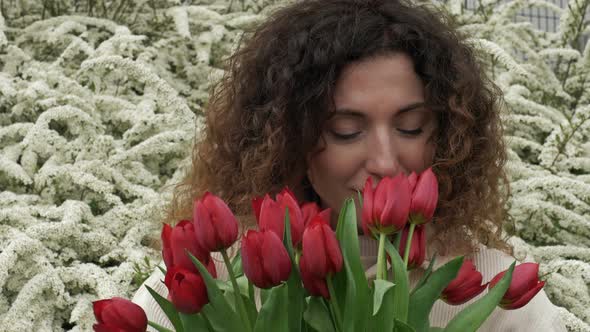 Portrait of a Happy Woman with a Bouquet of Red Tulips