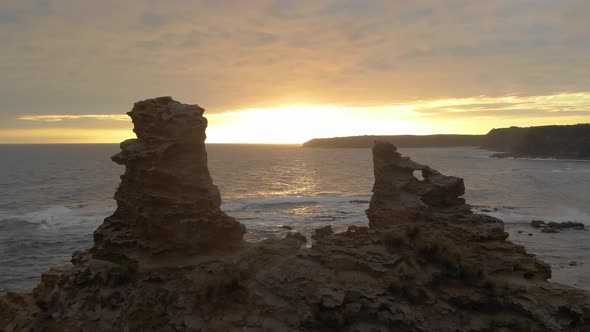 Aerial shot flying right in between the two peaks of eagles nest towards the sunset on the Victorian alt