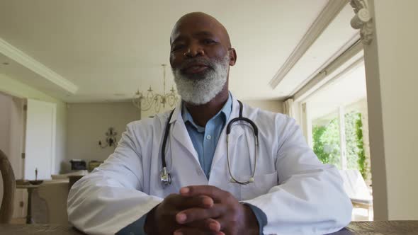 Portrait of african american senior male doctor talking looking at the camera at home alt