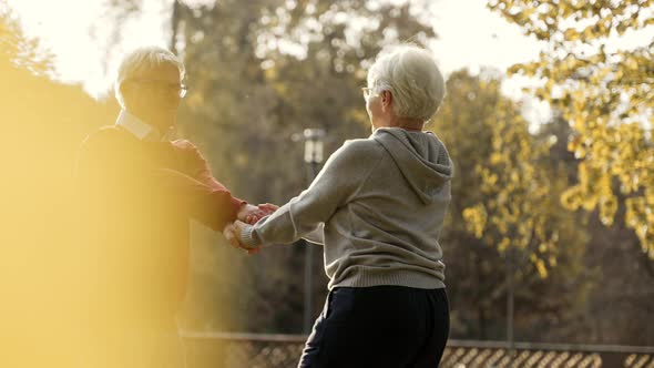 Middle Aged Caucasian Married People Dance in Park Holding Hands and Smiling Medium Shot alt