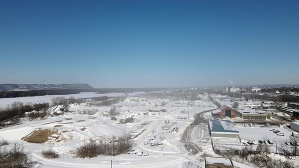 Aerial view of landscape covering the frozen river, mountains, blue sky and snow on the ground.