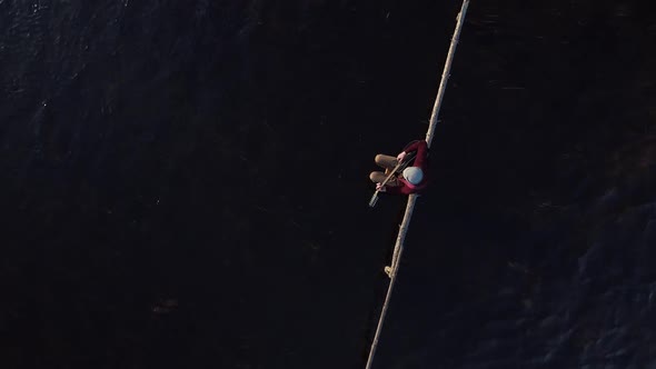 The Guitarist Sits on a Wooden Crossbar in the Middle of a Stream of Water and Plays a Black