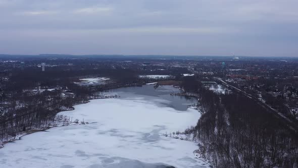 An aerial view from a drone, over a long lake during sunrise on a cloudy morning. The camera truck r alt