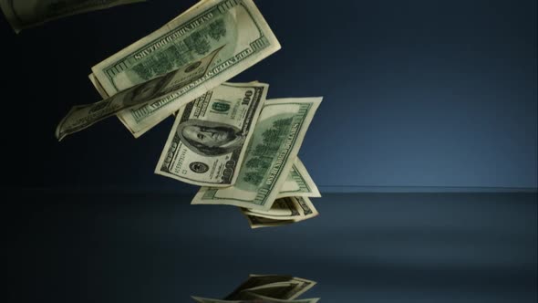 American $100 Bills Falling onto a Reflective Surface alt