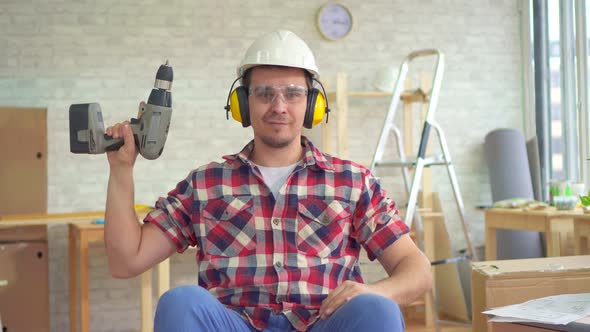 Portrait Young Disabled Man in a Wheelchair in a Helmet and with an Electric Drill in His Hand alt