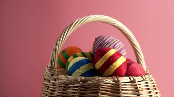 Rotation of Colorful Easter Egg in Basket Made From Threads Isolated on Pink Background