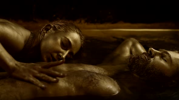 Sexy Lady is Seducing Sleeping Handsome Man Lovers are Lying in Golden Water alt